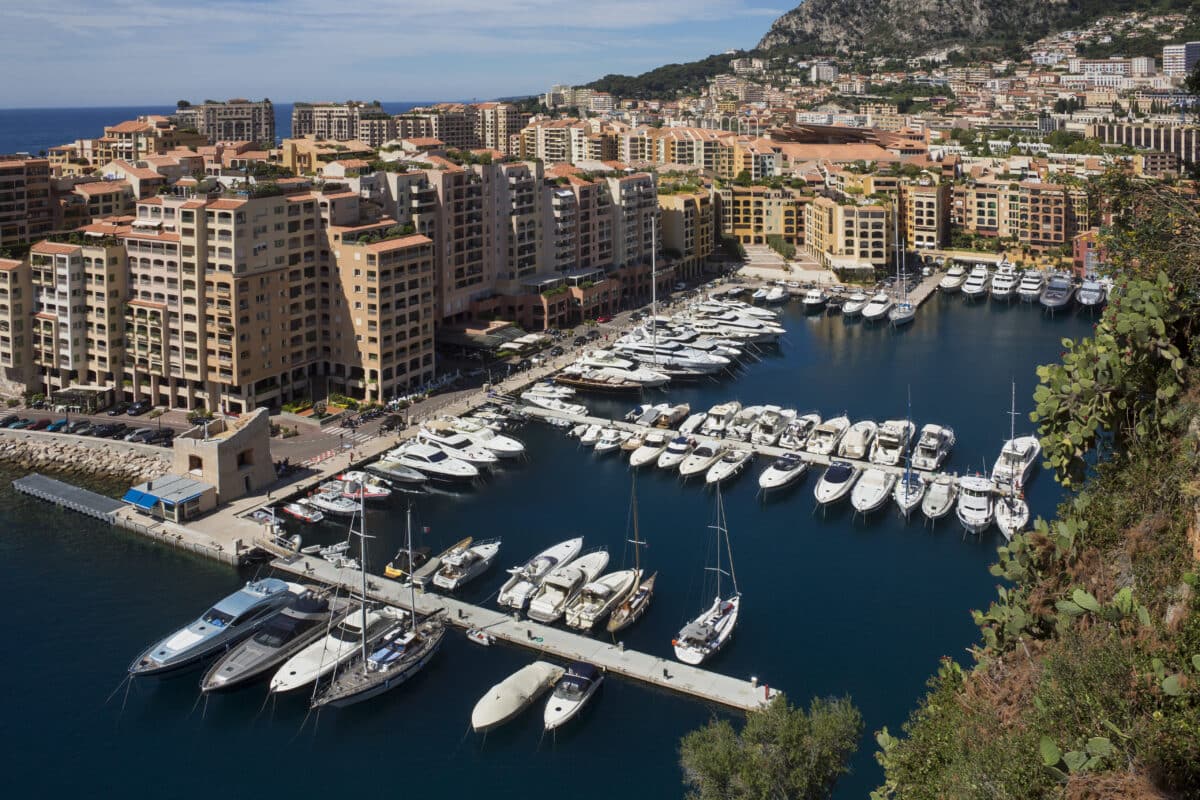 La vibrante Principauté de Monaco révèle ses charmes au travers de son port animé, où les terrasses des restaurants invitent à des instants de détente, tandis qu’un marché en arrière-plan suggère une incursion au cœur des saveurs et des couleurs locales.