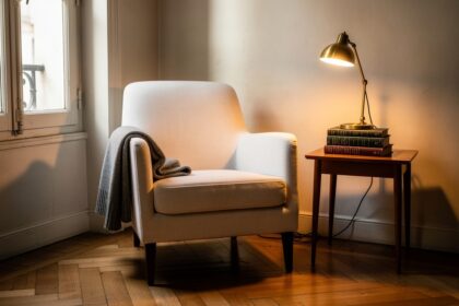 Coin lecture cosy aménagé dans un angle baigné de lumière, fauteuil scandinave et pile de livres.