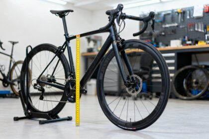 Vélo de route noir dans un atelier avec un mètre ruban posé le long du cadre