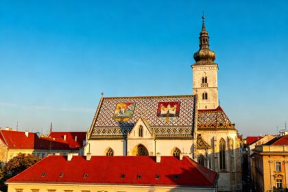 Vue de la ville haute de Zagreb avec un toit d'église aux tuiles colorées et des toits rouges