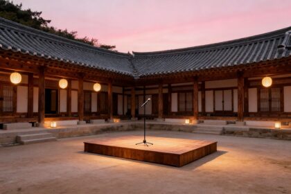 Cour intérieure d'une demeure traditionnelle coréenne au crépuscule, avec une petite scène en bois et un micro sous des lanternes.